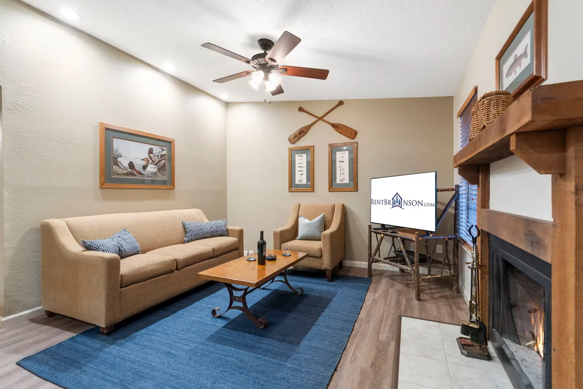A cozy, comfortable living area with a sofa, coffee table, fireplace, decorative oars, and tasteful artwork. The setting is inviting for families and provides a relaxing atmosphere after outdoor activities.