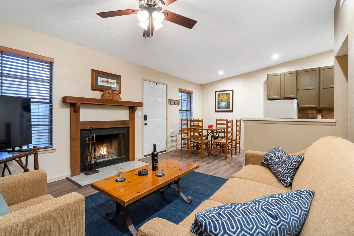 A warm and inviting living space featuring a crackling fireplace, a cozy sofa perfect for relaxing, and a dining table set for memorable meals or game nights—all bathed in soft, ambient lighting for a homey Ozarks retreat.