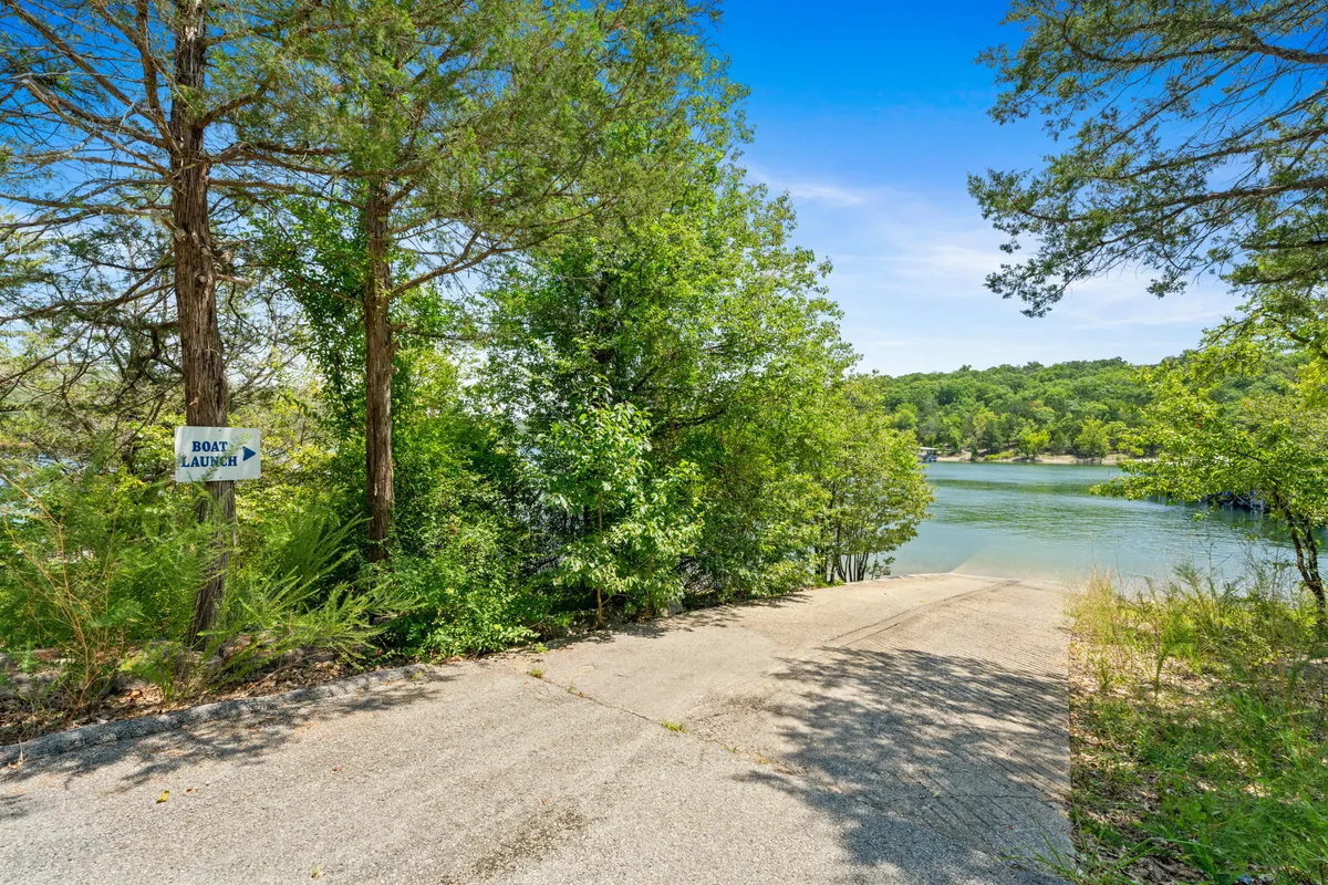 A tranquil exterior setting with a prominent boat launch sign at the water’s edge, framed by a tree line and open lake views. The image immediately communicates the functionality and excitement of launching a boat right from the property, with the relaxed lakeside atmosphere setting the scene for adventure.