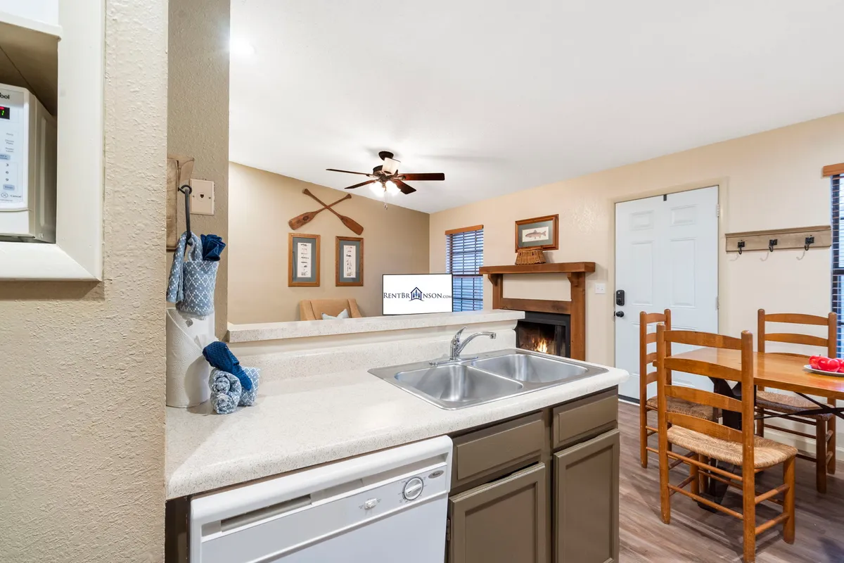 A cozy, inviting space with a kitchen sink, dining table, fireplace, and decorative paddles. The setup conveys warmth and togetherness, with a focus on family meals and relaxation by the fire.