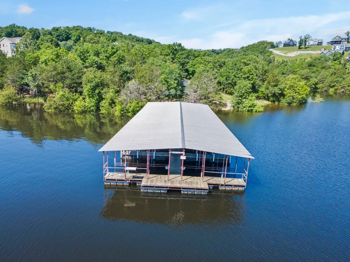 A dock extends over calm water, framed by lush greenery. The peaceful setting is ideal for enjoying a quiet morning coffee or relaxing while watching the sunset, embodying the spirit of a secluded, romantic retreat.