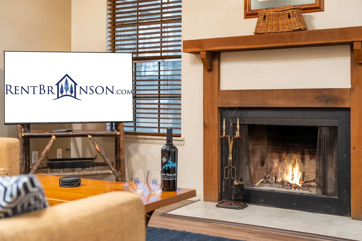 A closer look at the living area, highlighting a modern fireplace beneath a large smart TV. A bottle of wine sits on the coffee table, suggesting a relaxed, social atmosphere. The setting is staged for watching movies, enjoying drinks, or unwinding after a day of adventure.